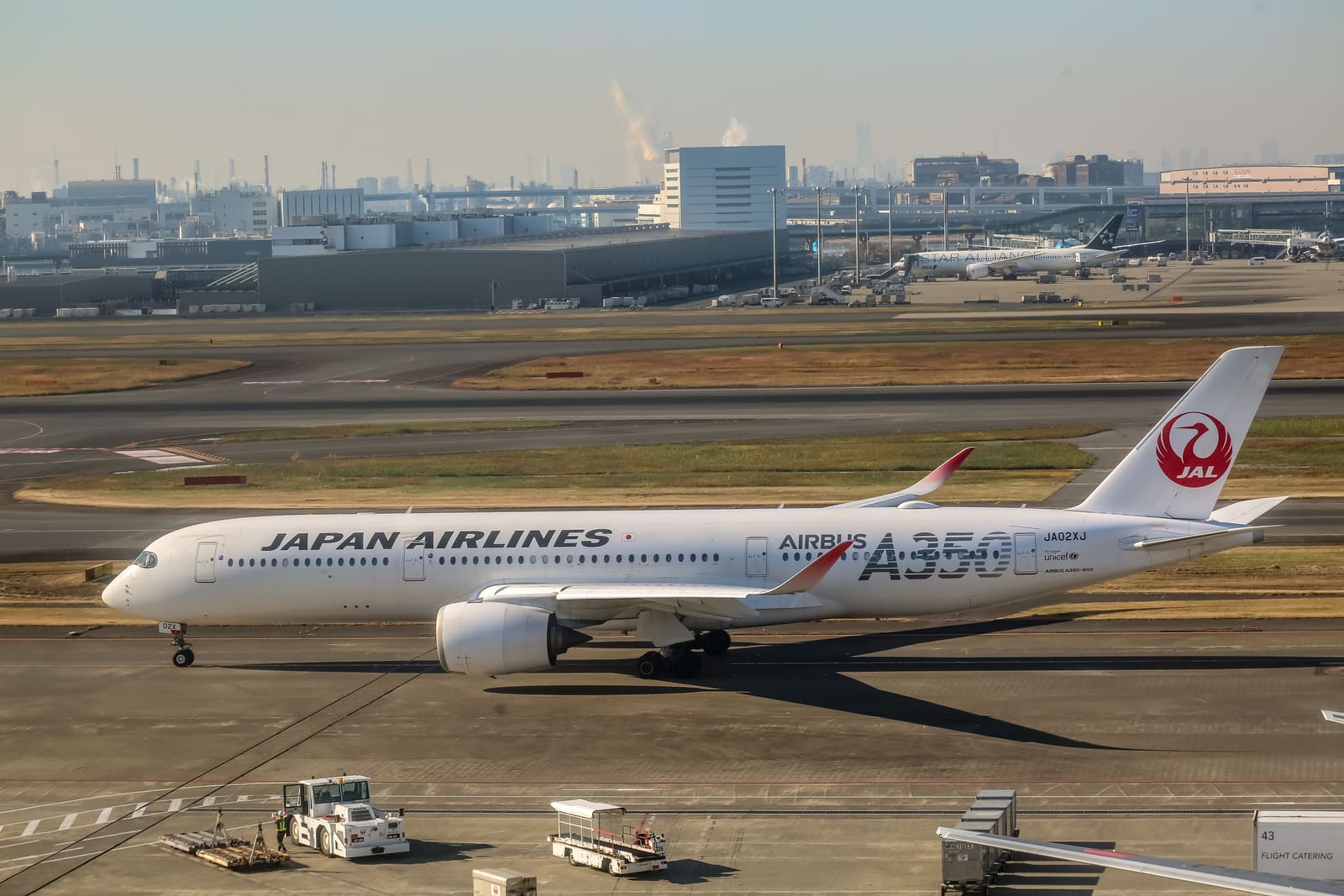 A Japan Airlines Airbus A350 taxiing at Haneda Airport with the Tokyo skyline visible in the background
